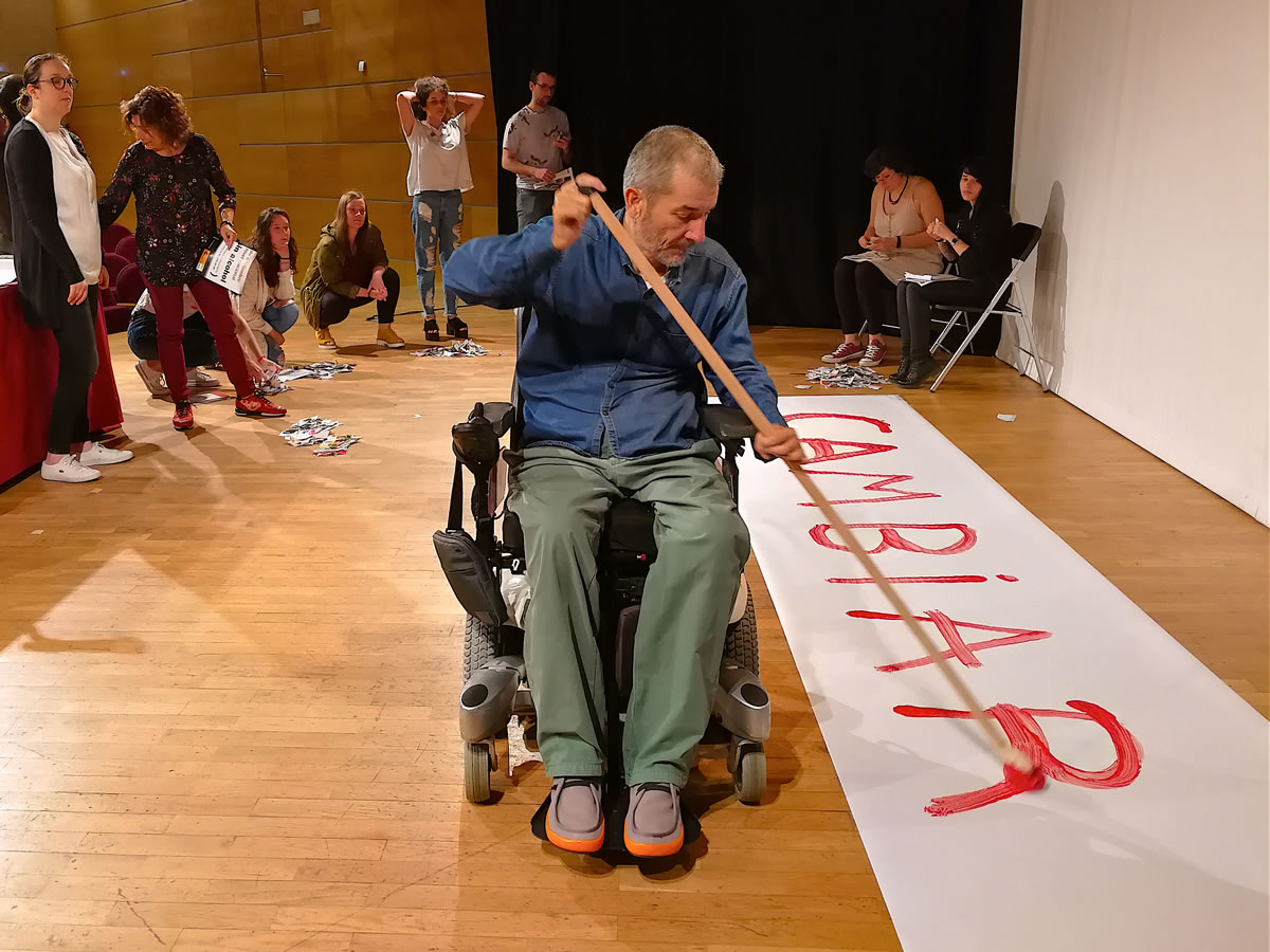 José Antonio Nóvoa pintando la palabra "cambiar" sobre una pancarta en el suelo
